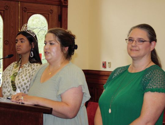 County 4-H Extension Agent Candace Williams, center, speaks to the Commissioner’s Court on July 12, sharing the special honor presented to Amanda Cowey, right, at the State 4-H Roundup. Cowey received the Salute to Excellence for her many years of 4-H volunteer service, including the Cuero...