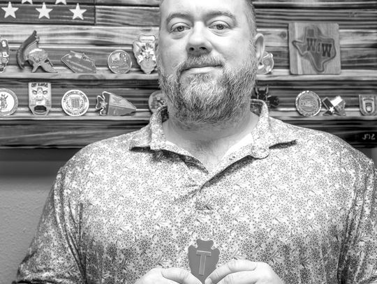 Zengerle holding up 36th ID Coin. The arrowhead shape represents Oklahoma and the “T” for Texas. This patch (Division) spanned from Texas through Oklahoma.