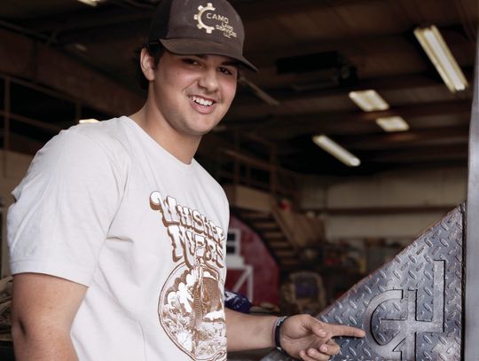 Landon Duckett points to the brand he designed on his flatbed project. (Photo by Ele Chew)