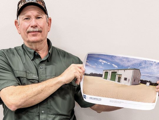 Commissioner Brian Carson holds up the architectural rendition of the new Pct. 4 of_ce and shop building to be located at 20 FM 236. (Photo by Ele Chew)