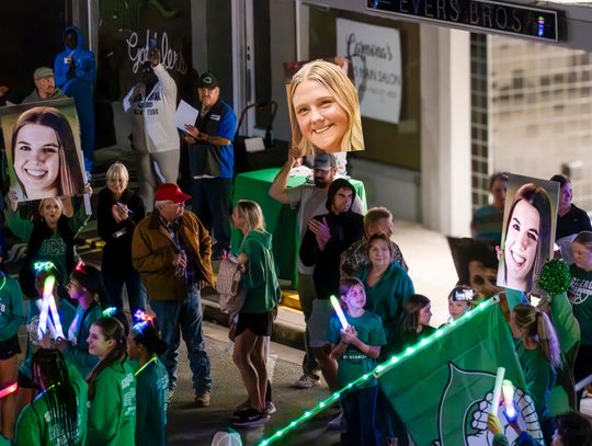 Parents hold up giant photos of their player daughters