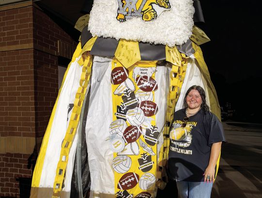 Emmalee Alatorre, the Lion’s Club September Teacher of the Month, shows off the Giant Mum her floral design students created for homecoming. During transport Friday, the ribbons were damaged, so the length was reduced. PHOTO BY ELE CHEW
