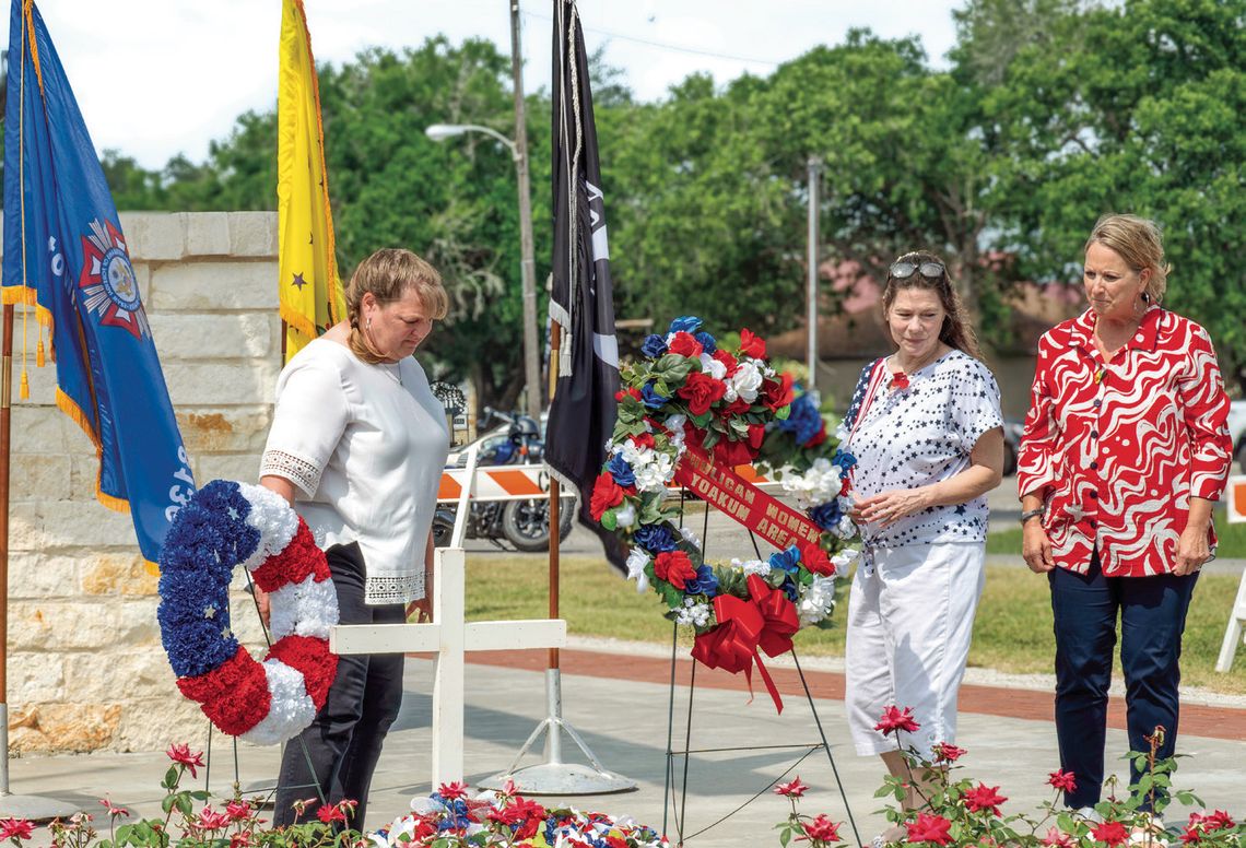 Members of the VFW Auxiliary Post 8136, from left, Valerie Chinnery, Heather Menn, and Laura Wauson lay the wreaths honoring the fallen dead at the May 26 Memorial Day Ceremony. PHOTO BY ELE CHEW
