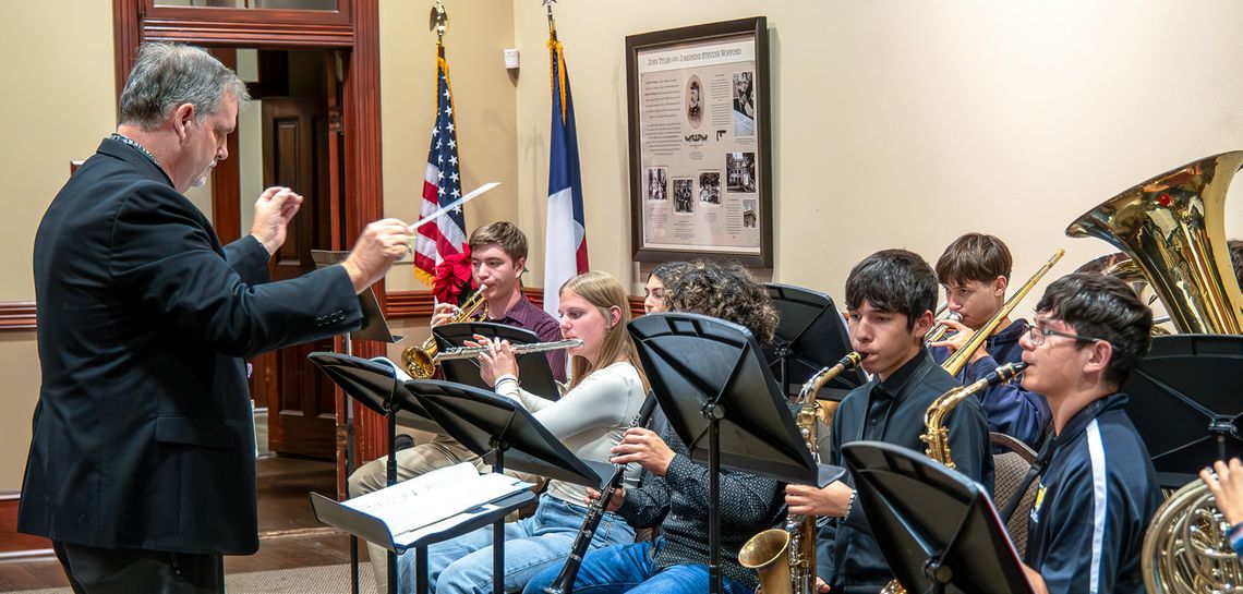 Band Director Larry Barnett led the Yorktown Wildcat Christmas Ensemble in Frosty the Snowman and Rudolph the Red-Nose Reindeer that warmly cheered the room. (Photo by Ele Chew)