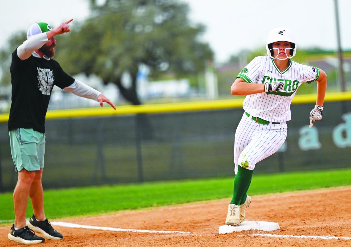 Caroline Kubesch rounds third base as Coach Cody Miller moves her onto home during the district match up with Gonzales on March 25. The Lady Gobblers won the game 6-3. (Photo by Courtney Kubesch)