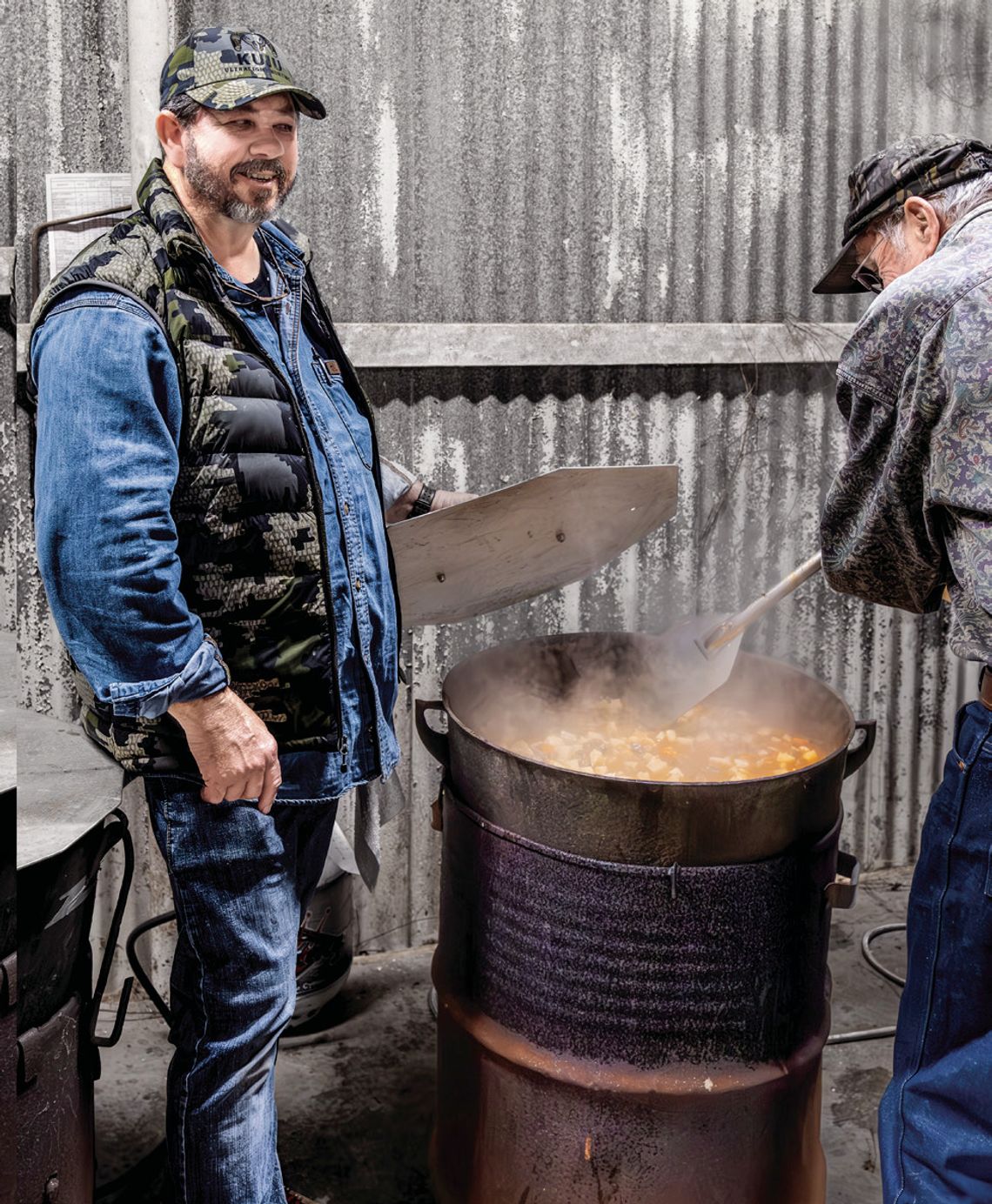 Stephen Lange and Darwin Jacob stir the stew with a paddle. (Photo by Ele Chew)