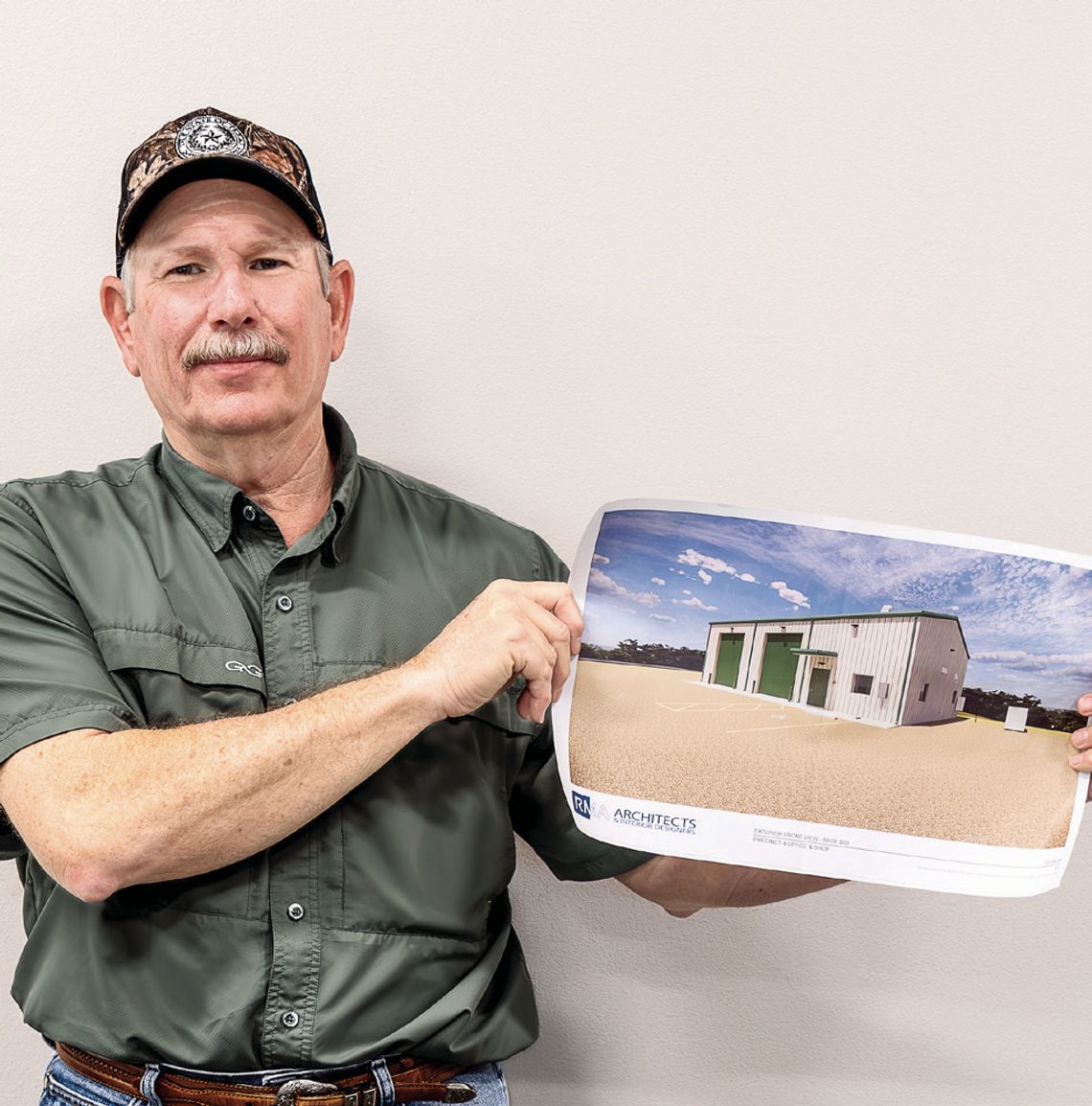 Commissioner Brian Carson holds up the architectural rendition of the new Pct. 4 of_ce and shop building to be located at 20 FM 236. (Photo by Ele Chew)