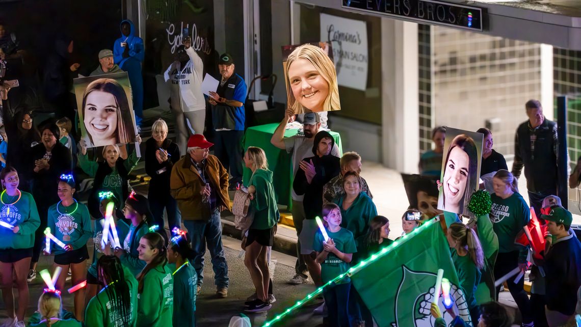 Parents hold up giant photos of their player daughters